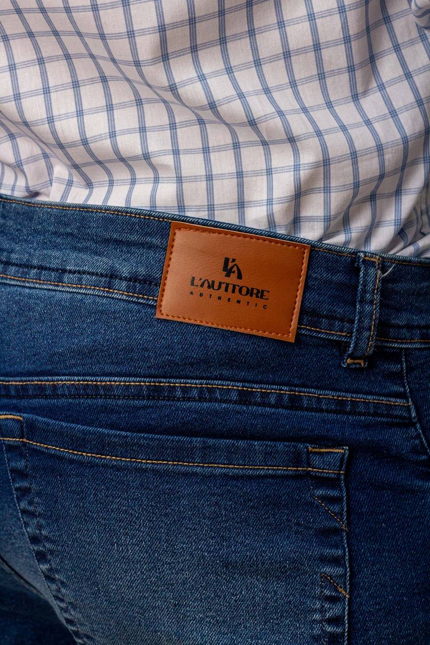 Detalhe macro do patch de couro L'Auttore Authentic e pespontos caramelo no denim